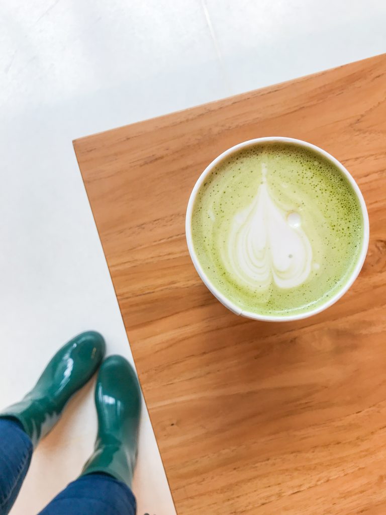 A matcha latte at Equator Coffee in San Francisco with the author's rain boots in the photograph