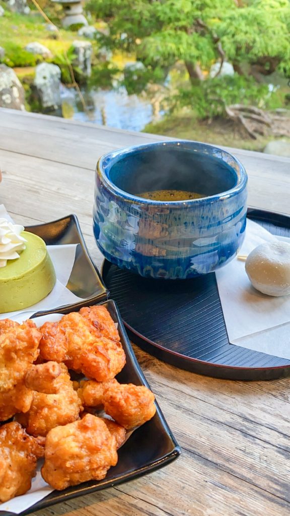 A cup of match with a red bean paste mochi, also a Green Tea Cheese Cake and chicken karaage overlooking the pond at the Japanese Tea Garden in San Francisco