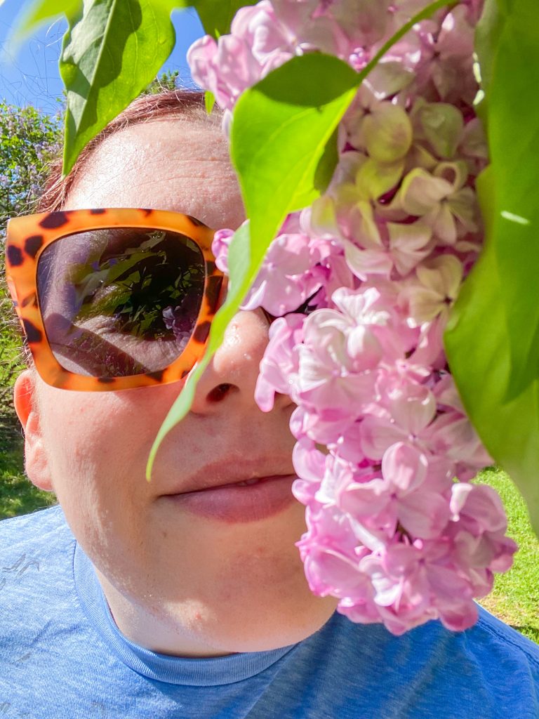 Author smelling lilacs on a sunny day at the Rochester Lilac Festival