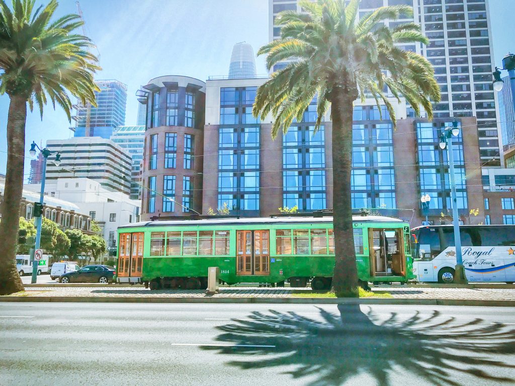 Downtown San Francisco, buildings in the background with the green trolley and palm trees